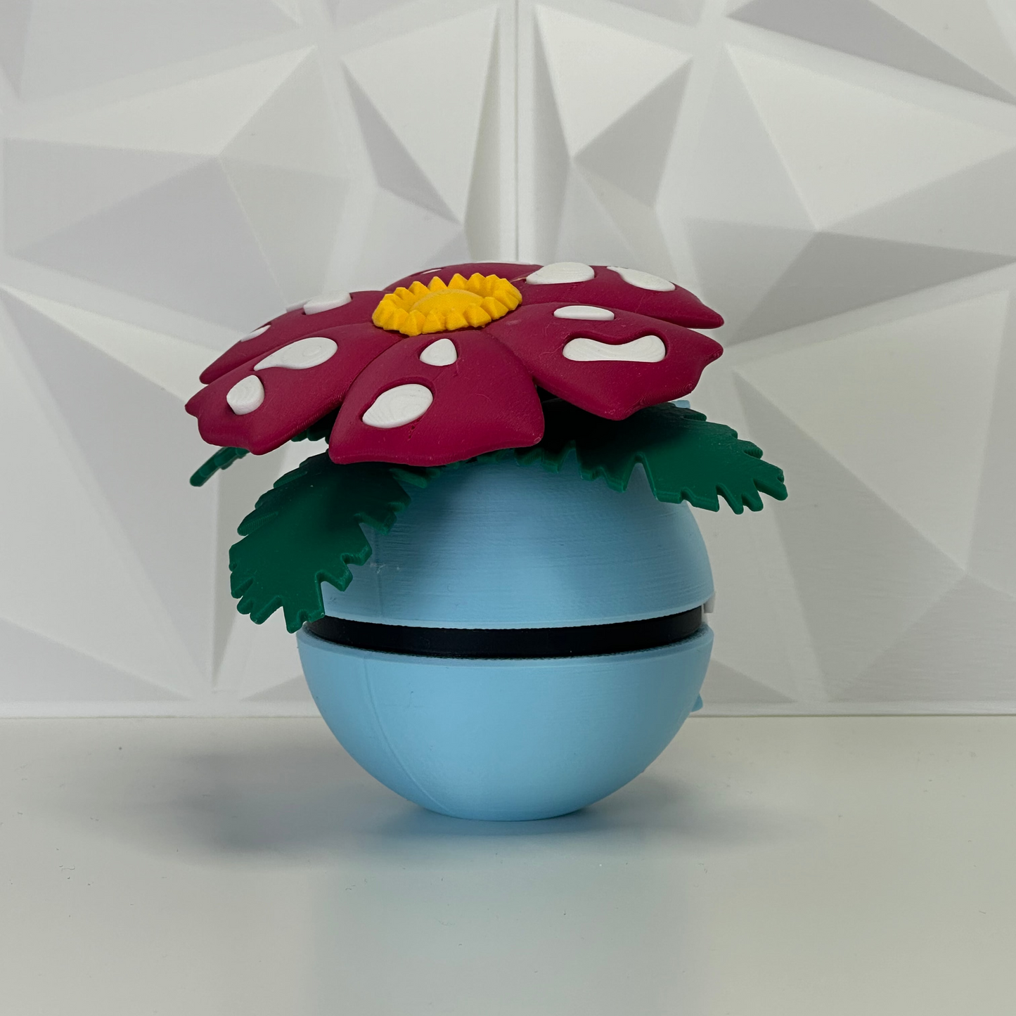 Parte trasera de figura Venusaur Pokéball, mostrando los grandes pétalos rosas con manchas blancas.